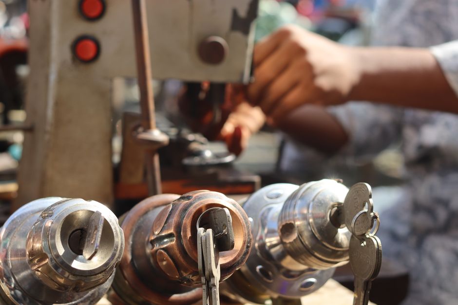 Close-up image of locksmith tools and hands working with a key machine outdoors. - Photo by Saad Bin Hasan on Pexels