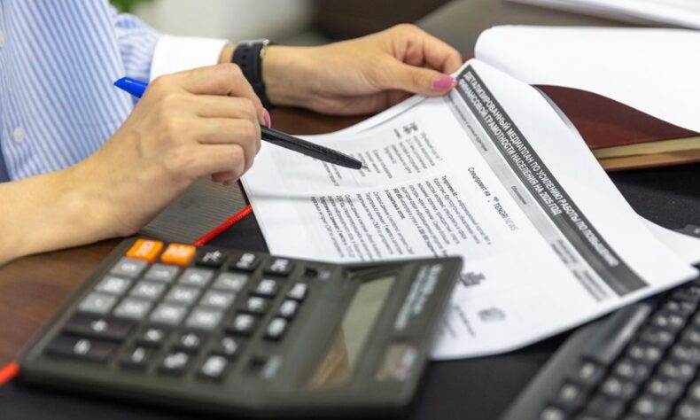 Close-up of a person analyzing financial documents using a calculator and pen. - Photo by Bia Limova on Pexels