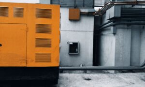 Outdoor view of an industrial generator with visible piping and wiring against a concrete wall. - Photo by ezrah lane on Pexels